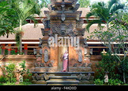 Touristen, die einen Beitrag in einer der kleinen Tempel im Bezirk Ubud während der religiösen Zeremonie geben. Stockfoto