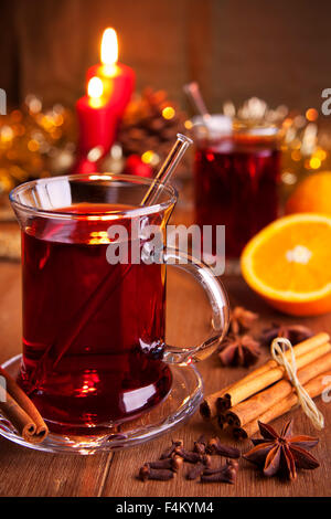 Ein Glas Glühwein oder Glühwein auf einem rustikalen Tisch mit Zutaten und Weihnachtsschmuck. Stockfoto