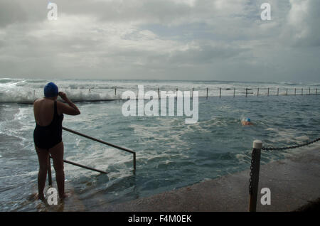 Eine ältere Frau bereitet sich auf das Schwimmen unter rauen Meeresbedingungen im Newport Beach Ocean Pool in Sydney, Australien, vor Stockfoto