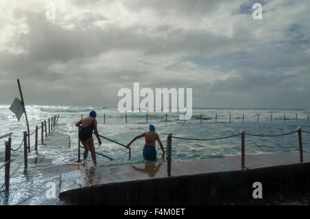 Ein älteres Paar schwimmen in Newport Beach Ocean Pool in rauher See am frühen Morgen in Sydney, Australien Stockfoto