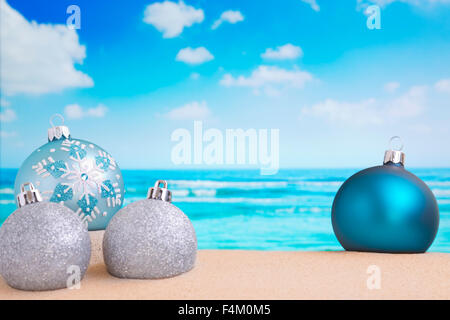 Weihnachtskugeln in den Sand am Strand auf einem hellen, sonnigen Tag. Stockfoto