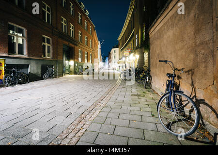 Fahrrad geparkt entlang einer schmalen Straße in der Nacht, in Kopenhagen, Dänemark. Stockfoto