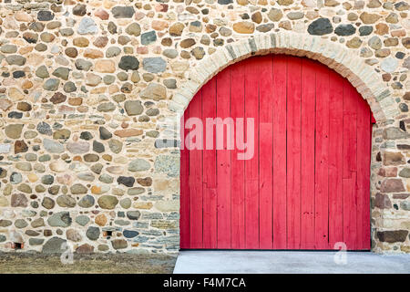 Leuchtend rot gewölbte Tür-Set in einem alten Steinmauer.  Viel Textur, Farbe und Handwerkskunst. Stockfoto