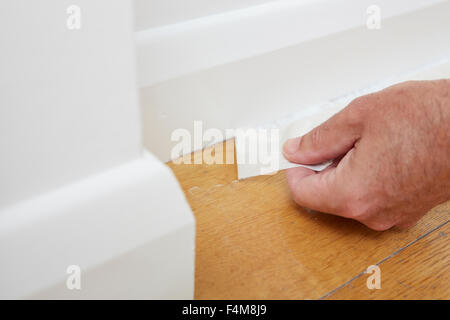 Nahaufnahme des Mannes Sockelleiste Klebeband entfernen Stockfoto