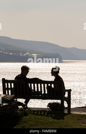 Ein junges Paar-Gespräch auf einer Bank mit Blick auf die britische Küste, England, UK Stockfoto