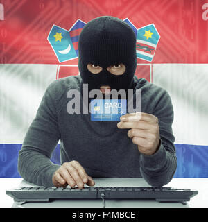 Dunkel-enthäutete Hacker mit Kreditkarte in der Hand und Flagge auf Hintergrund - Kroatien Stockfoto