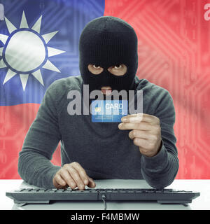 Dunkel-enthäutete Hacker mit Kreditkarte in der Hand und Flagge auf Hintergrund - Taiwan Stockfoto