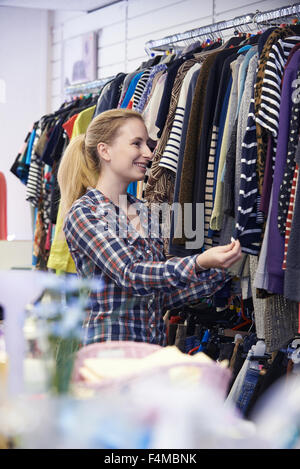 Weibliche Shopper im Secondhand-Laden Blick auf Kleidung Stockfoto