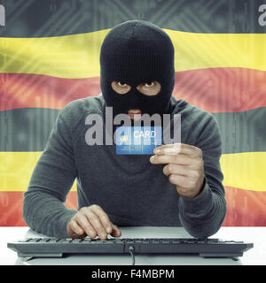 Dunkel-enthäutete Hacker mit Kreditkarte in der Hand und Flagge auf Hintergrund - Uganda Stockfoto