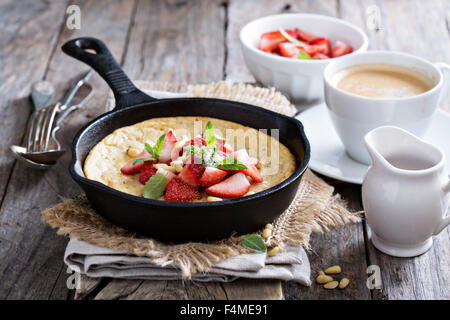 Gebackene Pfannkuchen in Gusseisen Pfanne mit frischen Erdbeeren und Pinienkernen Stockfoto