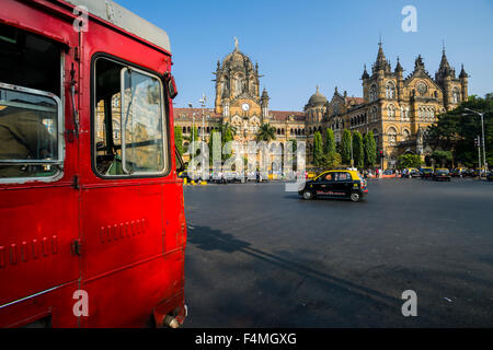 Die ehemalige Victoria Terminus Bahnhof, jetzt Chhatrapati Shivaji Terminus, über den Platz mit einem roten Bus Überfahrt gesehen Stockfoto