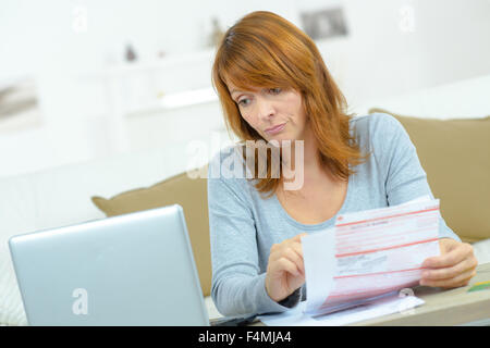 Frau mit Rechnungen und computer Stockfoto