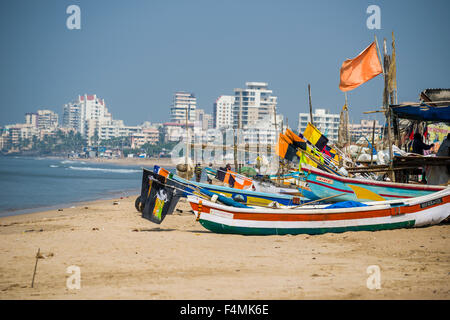 Wooden Fischerboote liegen auf dem Sand am Juhu Beach, die Skyline des modernen weißen Gebäude in der Ferne Stockfoto