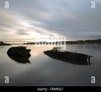 Schiffswracks von Bowling Harbour mit Erskine Bridge im Hintergrund bei Sonnenuntergang Stockfoto