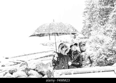 Snow in September and tourists shelter under an umbrella at Moraine Lake, Banff National Park, Rocky Mountains, Alberta, Canada. Stockfoto