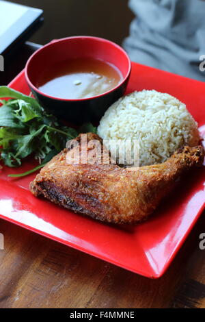 Huhn mit Reis mit Deep Fried Chicken und Brühe auf einer roten Platte Stockfoto