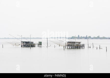 Zwei Fischerhütten am Meer in der Nähe von der Stadt Comacchio in Italien an einem bewölkten Tag Stockfoto