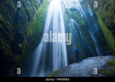 Person in der Schlucht unter Gljufurarfossi Wasserfall, Seljaland, Sudhurland, Island. Stockfoto