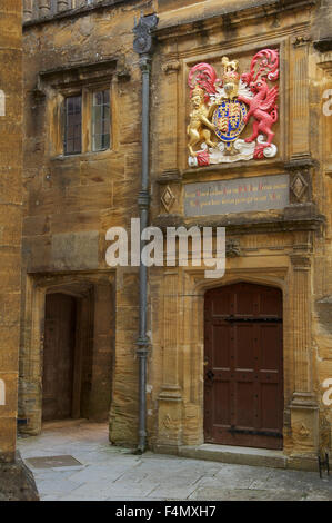 Einen kleinen abgeschiedenen Innenhof in Sherborne School. Über eine Tür ist das königliche Wappen von König Edward 6. Dorset, England, Vereinigtes Königreich. Stockfoto