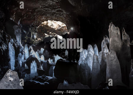 Person unter Eis Stalagmiten in Raufarholshellir Lavaröhre, in der Nähe von Hveragerdi, Sudherland, Island. Stockfoto