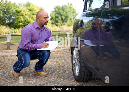 Mann, die Überprüfung der Seite eines Autos Stockfoto