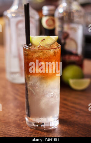 Dunklen und stürmischen Cocktail in einer Bar top mit Flaschen und Kalk im Hintergrund Stockfoto