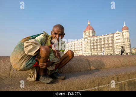 Ein Bettler sitzt vor dem sehr luxuriöse und teure taj mahal palace hotel im Stadtteil Colaba Stockfoto