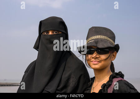 Ein Porträt von zwei muslimischen Frauen im Gegensatz zu jeder anderen, eine in der traditionellen schwarzen Burka, Hijab bekleidet, und der andere Ich Stockfoto