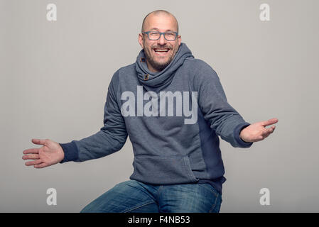 Charismatische Glatzenbildung Mann mittleren Alters mit Brille Lachen und zuckend zu zeigen, seine Unwissenheit sitzen obere BSB Stockfoto