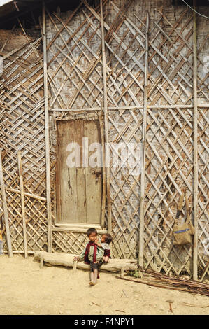 Nagaland, Indien - März 2012: Kleine Kinder sitzen vor Traditionshaus in Nagaland, abgelegenen Region von Indien. Dokuments Stockfoto