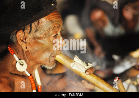 Nagaland, Indien - März 2012: Alte traditionelle Halskette mit bemaltem Gesicht raucht Pfeife in Nagaland, abgelegenen Region von Indien Stockfoto