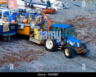 New Holland Traktor auf Cadgwith Strand, Halbinsel Lizard, Cornwall, England, Vereinigtes Königreich Stockfoto