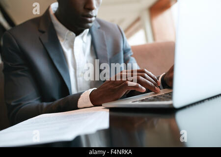 Schuss von männlichen Händen tippen auf Laptoptastatur hautnah. Afrikanische Unternehmer arbeiten auf Laptop-Computer im Café. Stockfoto