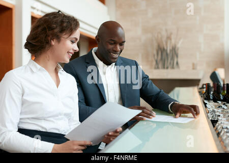 Glückliche junge Geschäftsleute einige Dokumente zu lesen und Lächeln auf den Lippen. Führungskräfte mit Geschäftsberichten im Café sitzen. Stockfoto