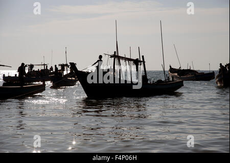 Silhouetten der birmanischen Fischer aus laden ihre Boote bei Sonnenuntergang am Ngapali Strand Myanmar Stockfoto