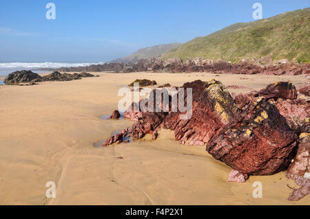 Schöner Strand am Freshwater West in Pembrokeshire, Wales. Ein sonniger Vormittag am Strand mit roten Felsen und Sand ausgesetzt. Stockfoto