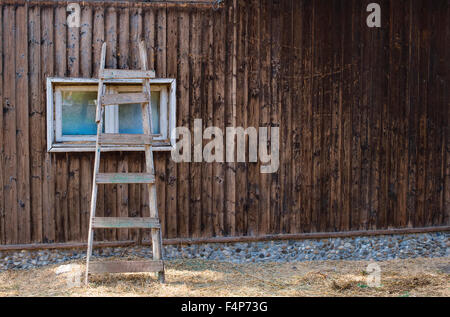 Alte Leiter lehnt sich an ein Haus aus Holz Stockfoto