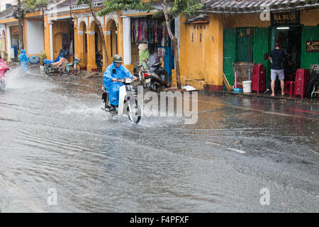 Hoi an eine alte Stadt Vietnam, überfluteten Straße durchfährt Biker auf Roller Motorrad während eines Gewitters, Vietnam Stockfoto