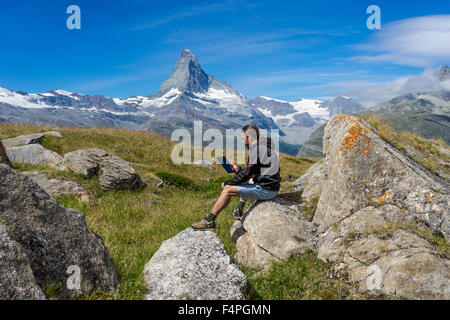 Robuste Wanderer liest aus einem smart Tablet unter Matterhorn Gipfel. Juli 2015. Matterhorn, Schweiz. Stockfoto