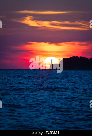 Segelboot und Leuchtturm an dramatischen Sonnenuntergang in Zadar, Dalmatien, Kroatien Stockfoto