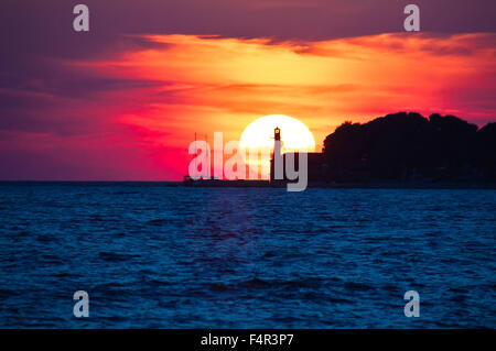 Epische Blick auf den Sonnenuntergang mit Leuchtturm und Saiboat in Zadar, Dalmatien, Kroatien Stockfoto