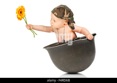 Niedlichen Mädchen mit Blume in einer alten militärischen Helm Stockfoto