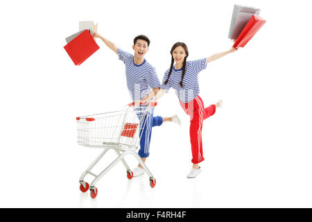 Glückliche junge Männer und Frauen schieben Einkaufswagen Stockfoto