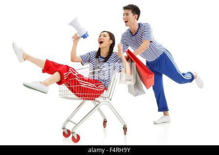 Glückliche junge Männer und Frauen schieben Einkaufswagen Stockfoto