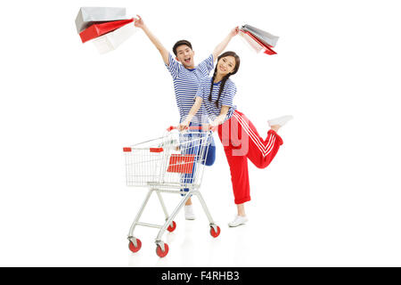 Glückliche junge Männer und Frauen schieben Einkaufswagen Stockfoto