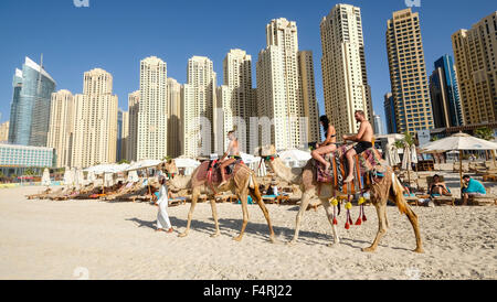 Touristen, die Reiten Kamel am Strand im JBR Jumeirah Beach Residences im Marina District von Dubai Vereinigte Arabische Emirate Stockfoto