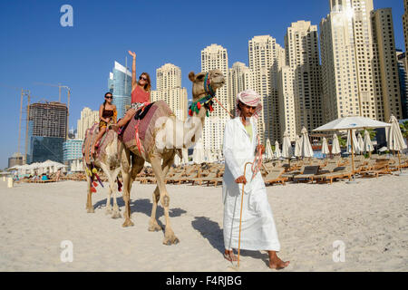 Touristen, die Reiten Kamel am Strand im JBR Jumeirah Beach Residences im Marina District von Dubai Vereinigte Arabische Emirate Stockfoto