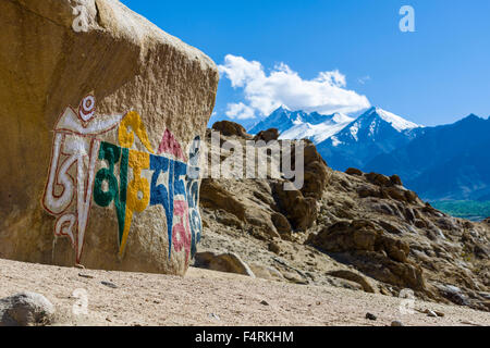 Ein großer tibetean mani Stein mit dem Mantra Om Mani Padme Hum farbenfroh eingraviert ist auf einem Hügel über dem Tal des Indus Stockfoto