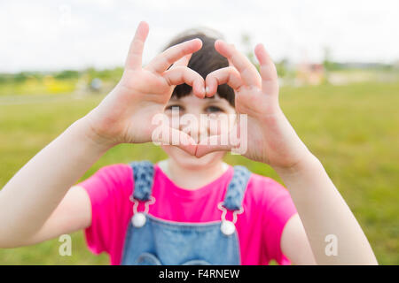 glückliche kleine Mädchen Herz Form Geste Stockfoto