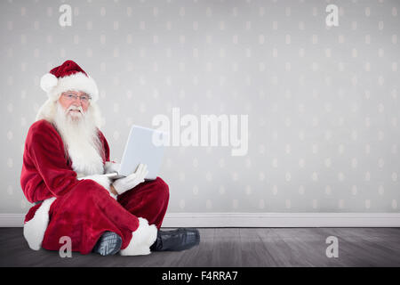 Zusammengesetztes Bild von Santa sitzt und einen laptop Stockfoto